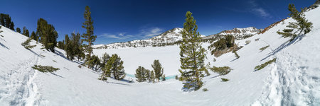Pacific Crest Trail. A snow covered mountain range with a lake in the foreground. The sky is clear...