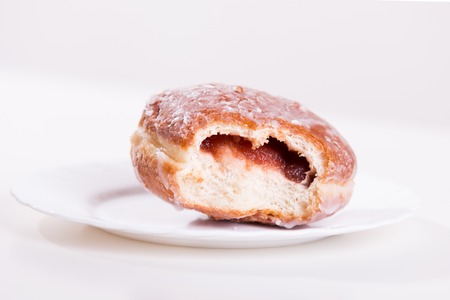 Bitten donut with jam lies on a plate - studio shootの写真素材