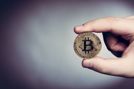 Bitcoin cryptocurrency gold coin in mans hand