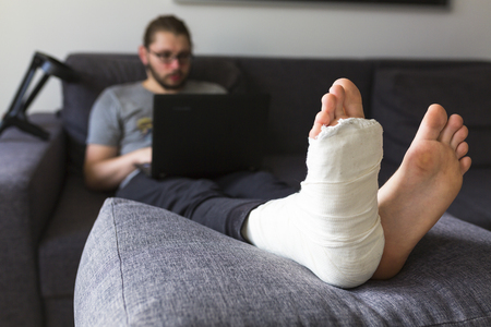man with a broken leg is surfing the internetの写真素材