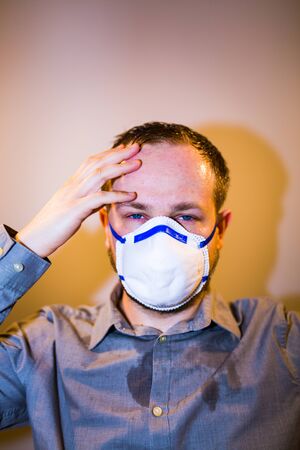 Man with real Coronavirus COVID-19 disease symptoms wears a protective maskの写真素材