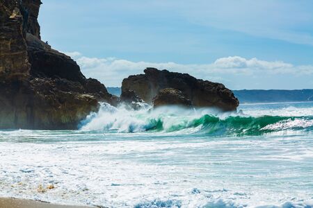 Big waves crash into the rocks of North beach in Nazare city, Portugalの写真素材