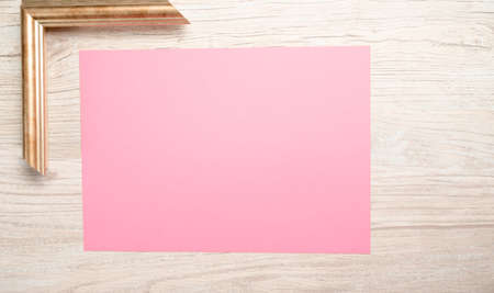 pink paper for text with golden frame and wooden backgroundの写真素材