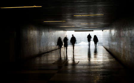 tunnel with light at the exit with people in motionの写真素材
