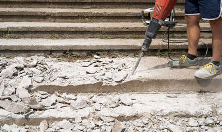 construction worker with a jackhammer, renovation of stairs, crushing the surface of stairs with a jackhammerの写真素材