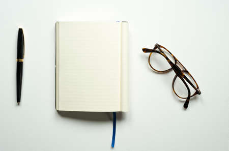 notebook with space for text, office, blue bookmark, brown glasses, pen, on a white background, top...