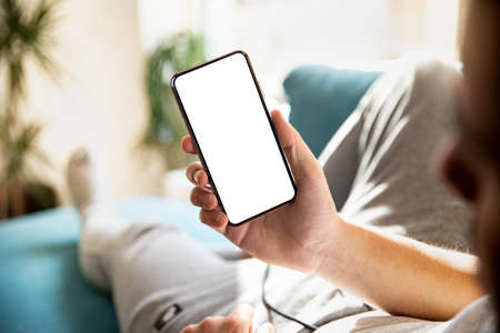 Man using smartphone frameless mockup blank screen in home interior