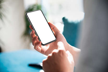 Man using smartphone frameless mockup blank screen in home interior