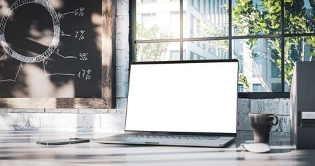Laptop with the blank screen on the office table. Window with trees in the backgroundの写真素材