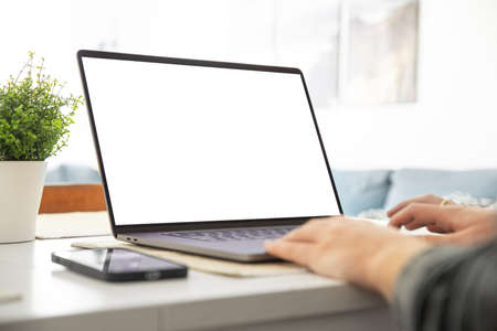 Man working on a laptop with a blank screen at his deskの写真素材