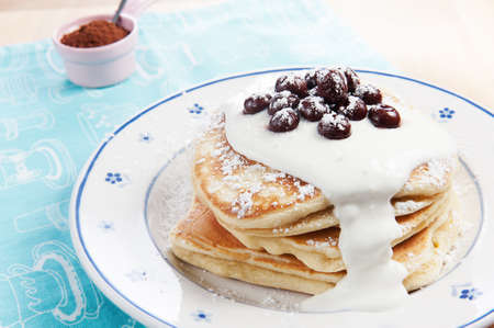 Stack of pancakes with yoghurt and cherries.