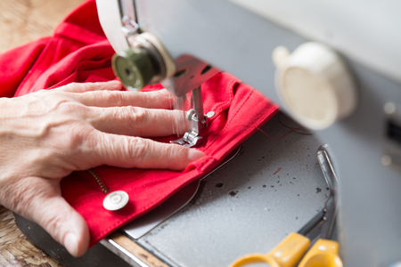 Older woman is sewing on a vintage machine.の写真素材