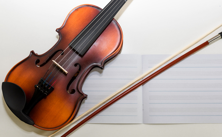 A Small Children's Violin and Bow on a Child's Study Desk. Colorful letters / magnets in the background. A set-up for teaching children to play the violin.の写真素材