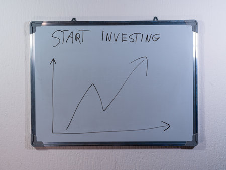 Whiteboard showing START INVESTING message with upward chart representing beginning investment journey and financial growthの写真素材