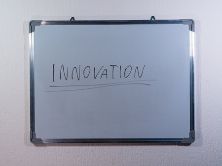 Whiteboard showing INNOVATION concept on clean white wall background representing creativity, new ideas and business developmentの写真素材