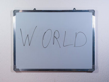 Whiteboard showing WORLD concept on clean white wall background representing global perspective, society and international connectionsの写真素材