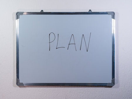 Whiteboard showing PLAN concept on clean white wall background representing planning, strategy and goal settingの写真素材