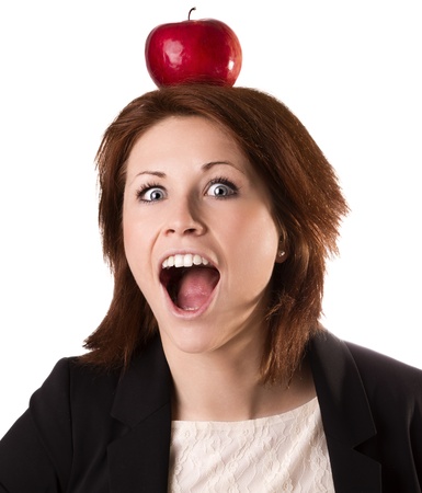 Young surprised businesswoman balancing an apple over head, isolated on whiteの写真素材