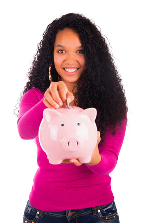 Young african american woman putting coin in piggy bank isolatedの写真素材