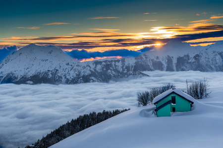Alpine hut in the snow during sunsetの写真素材