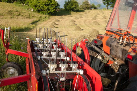 detail of a tractor in front of hay bales during the works of autumn seasonの写真素材