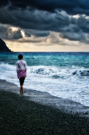 Girl walking by the sea before the stormの写真素材