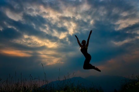 Jump in the mountains at dusk Girl in silhouetteの写真素材