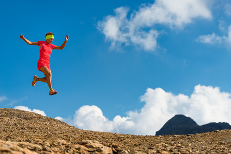 Girl makes a jump while running in the mountainsの写真素材