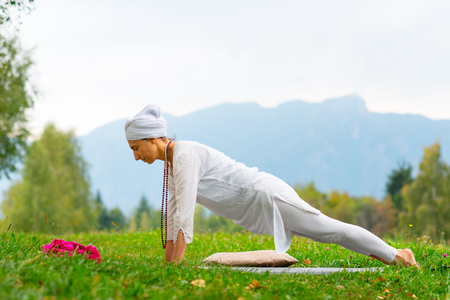 Girl practicing yoga in a meadow in the mountainsの写真素材