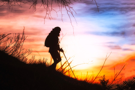 Girl hiking in silhouette in the sky coloredの写真素材