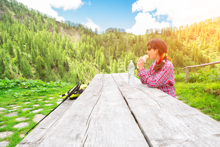 Girl eats in wooden table during remarried a mountain trekkingの写真素材