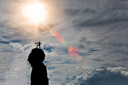 lone climber on the summit of the mountain after the conquest preparing the rope for the descent in a fantastic skyの写真素材