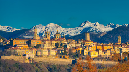 The city of Bergamo with high behind the White Mountains of snow the early morning sunの写真素材