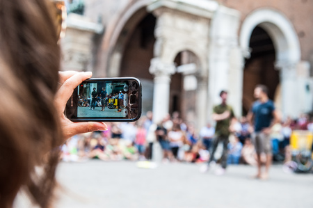 Ferrara, Italy - August 12, 2012: Girl realizes video clip with her smartphone during street performances at the busker festival in Ferraraのeditorial素材