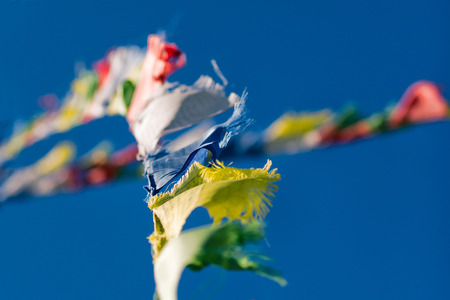Colorful Tibetan Buddhist prayer flags waving in the wind on blue sky background - selective focus.の写真素材