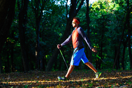 Nordic walking in the autumn forest between the leaves.の写真素材