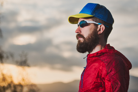 Portrait of young sportsman with beard during resting in the mountains.の写真素材