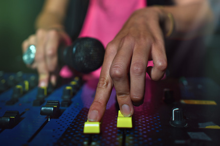 Close-up of female hands on a deejay console with microphone.の写真素材