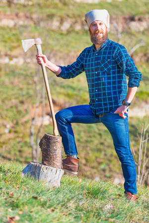 Young lumberjack with beard holds his ax in his hand.の写真素材