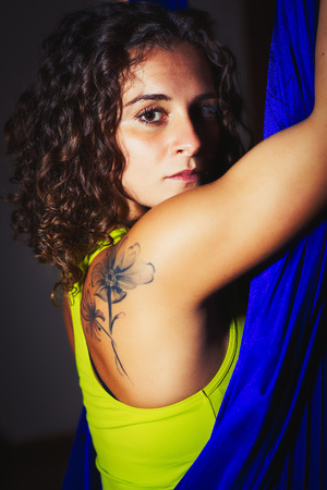 Closeup portrait of girl posing in a blue silk hammock - aerial anti-gravity yoga concept.の写真素材