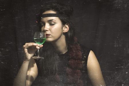 1920s style woman with glass of absinthe. Vintage style photography with reconstructed artifacts.の写真素材