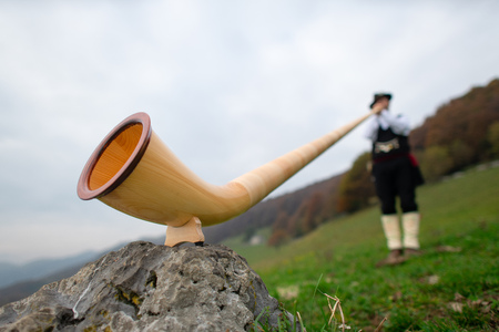 Alpine horn. A man plays in an alpine valley.の写真素材
