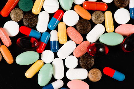 Colored drugs in capsules on a black background.