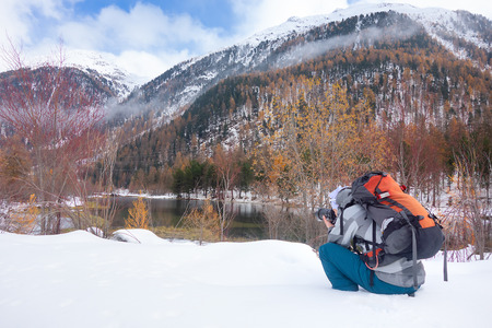 Photographer on the snow in autumn in front of a mountain lake.の写真素材