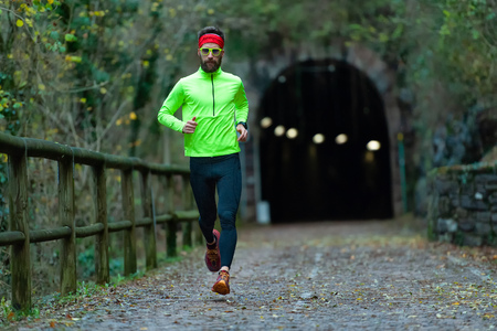 Man athlete runs on bike path between tunnels in the fall.のeditorial素材