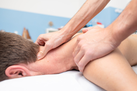 Therapist massaging the neck of young man.の写真素材