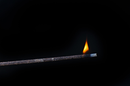 Eastern incense stick with burning flame on black background.の写真素材