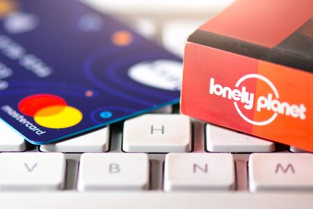 SAN PELLEGRINO TERME, ITALY - DECEMBER 7, 2018: A computer keyboard with MASTERCARD and Lonely Planet travel guideのeditorial素材