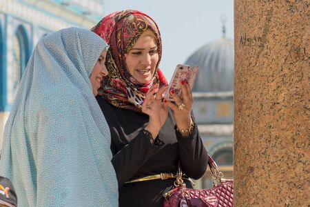 JERUSALEM, ISRAEL - APRIL 30, 2015: Arab women with veil watch smartphone in the esplanade of the mosquesのeditorial素材
