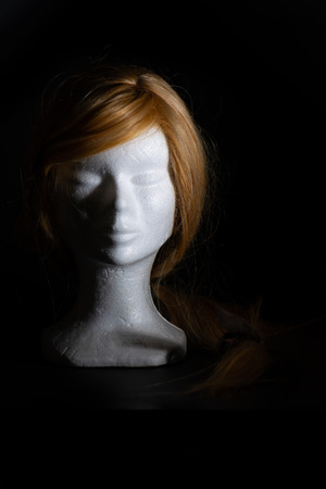 Blonde wig on a polystyrene head on a black backgroundの写真素材